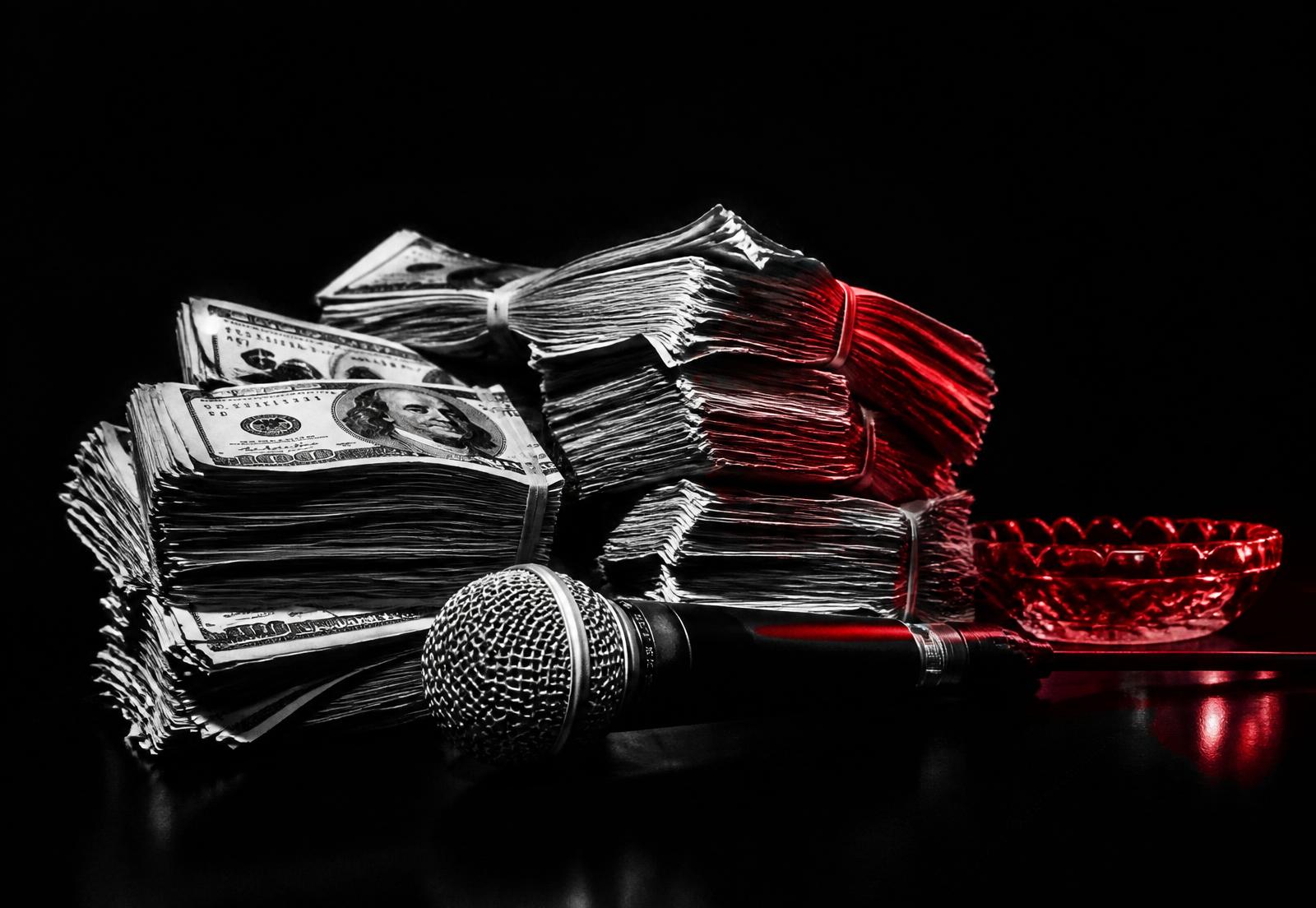 Stacks of cash and a microphone under red light